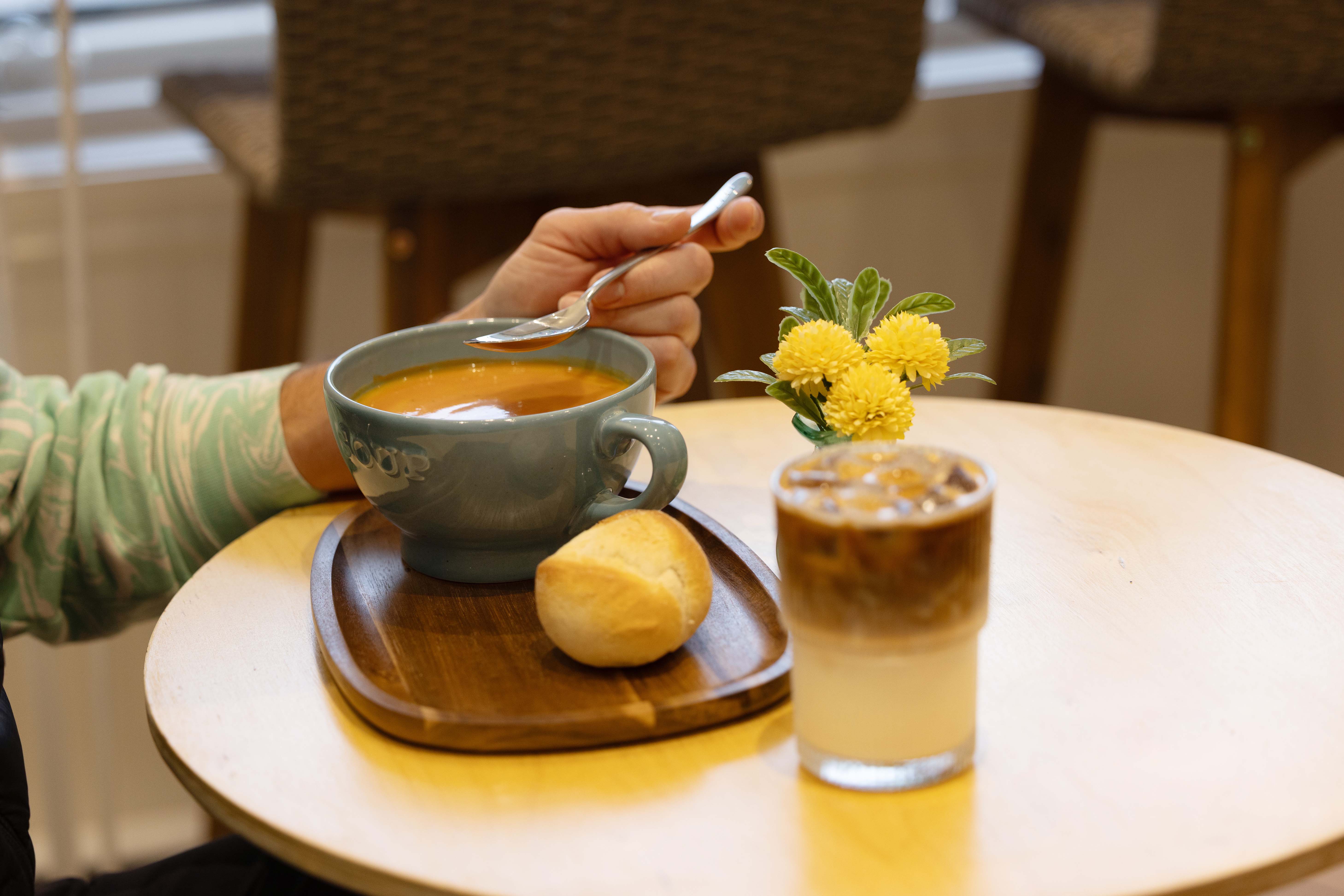 Une soupe avec un petit pain et un café glacé