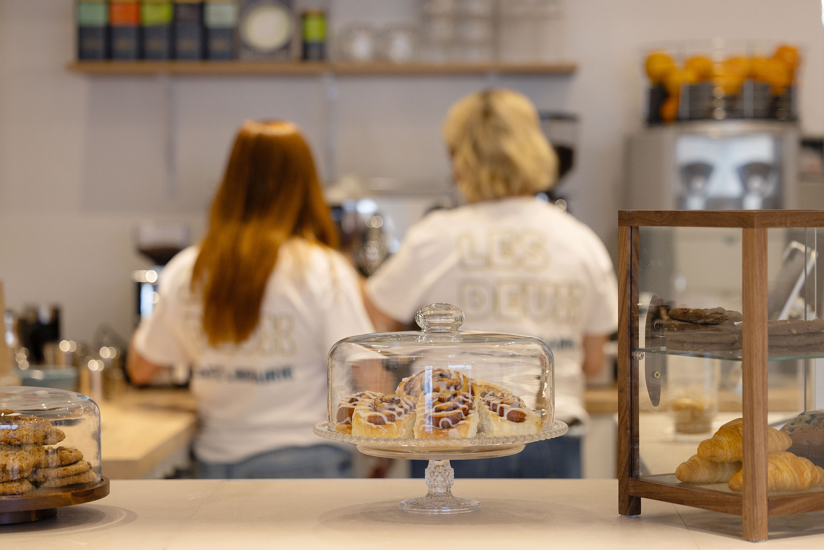 Deux baristas avec des pâtisseries dans un café librairie de quartier